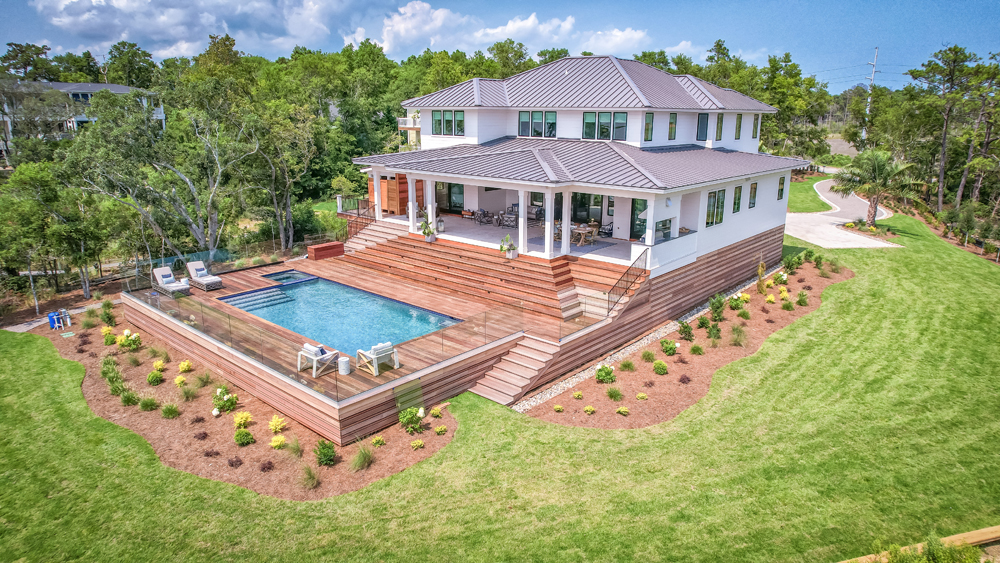 A large modern house with a pool and landscaped yard, surrounded by trees and open space.